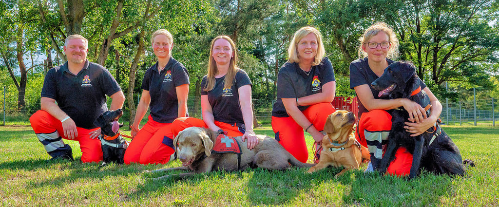 Alexander Koch (v.l.), Alexandra Koch mit Hildi (Labrador Retriever), Julia Reinecke mit Teddy (Labrador-Mischling), Madeleine Bohne mit Yuna (Labrador Retriever) und Jennifer Hans mit Matthea (Flat Coated Retriever) sind Mitglieder der BRH Rettungshundestaffel Magdeburg-Elbeland, die auf einem Trainingsplatz in Wahlitz ein neues Zuhause gefunden hat.