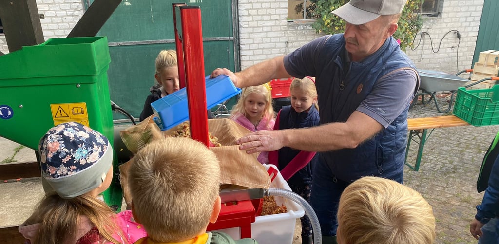 Detlef Braune mit Kindern an einer handlichen Saftpresse. Die im September angekündigte wird deutlich größer sein und mehr Äpfel schaffen.