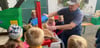 Detlef Braune mit Kindern an einer handlichen Saftpresse. Die im September angekündigte wird deutlich größer sein und mehr Äpfel schaffen.