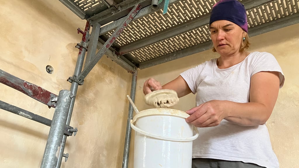 Restauratorin Susanne Fuchs streicht die Wände im Chorraum der Kirche neu ein.