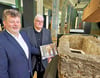 Die Fördervereinsvorsitzenden Thomas Nawrath und Rainer Kuhn präsentieren im Dommuseum in Magdeburg den  Kalender vor dem vor genau 24 Jahren entdeckten steinernen Grab.