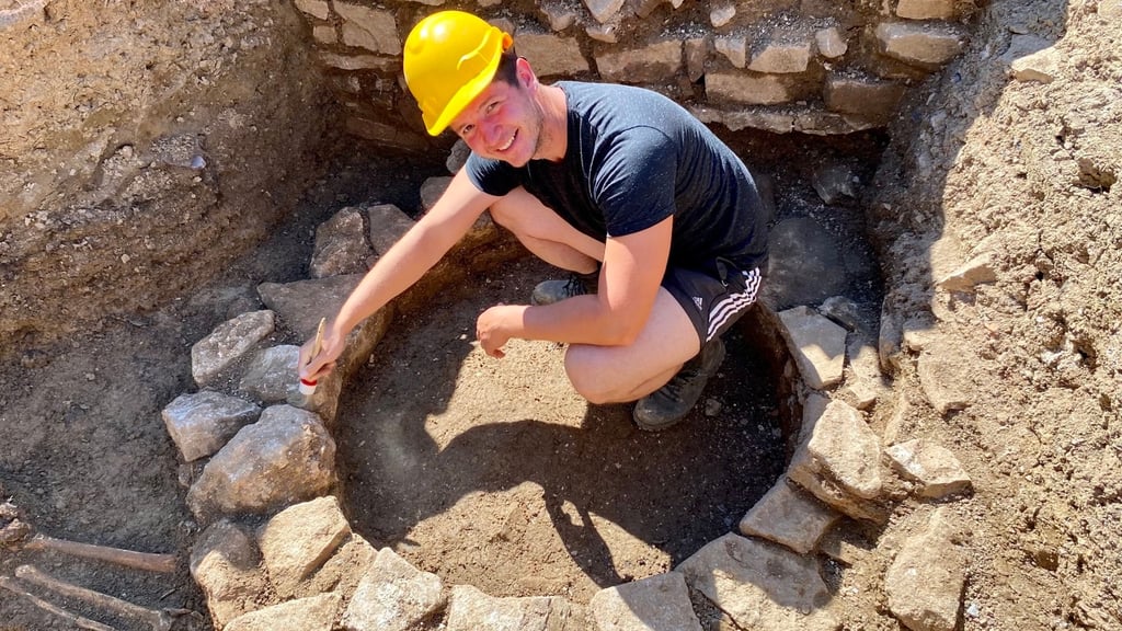 Dort, wo einst Menschen bestattet wurden, wurde später ein Brunnen errichtet: Archäologie-Student Robert Prust reinigt die dazugehörigen Mauerreste, auf die Forscher bei Grabungen an der Himmelpforte nahe Wernigerode gestoßen sind.