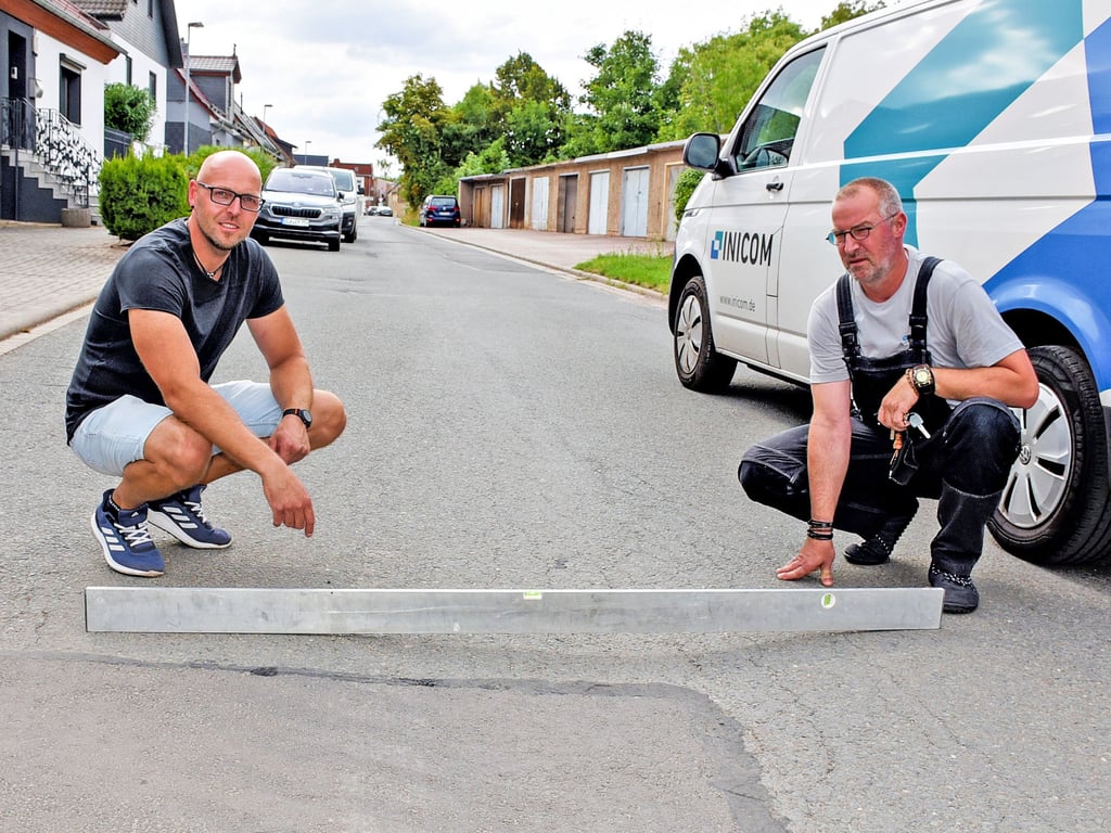 Steven Goldschmidt und sein Nachbar zeigen mit einer Wasserwaage, dass die Wilhelm-Bieser-Straße in Hecklingen keine gerade Fahrbahndecke hat und dadurch bei einer Überfahrt der schweren großen Landtechnik noch mehr Lärm verursacht.