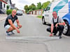 Steven Goldschmidt und sein Nachbar zeigen mit einer Wasserwaage, dass die Wilhelm-Bieser-Straße in Hecklingen keine gerade Fahrbahndecke hat und dadurch bei einer Überfahrt der schweren großen Landtechnik noch mehr Lärm verursacht. 