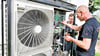 Handwerker stellen eine Wärmepumpe ein.