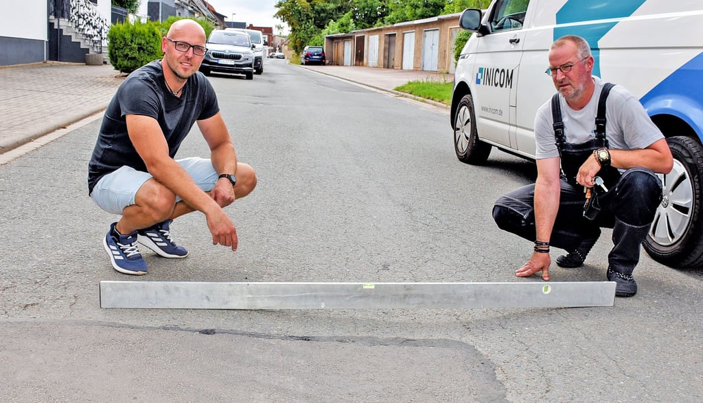Steven Goldschmidt und sein Nachbar zeigen mit einer Wasserwaage, dass die Wilhelm-Bieser-Straße in Hecklingen keine gerade Fahrbahndecke hat und dadurch bei einer Überfahrt der schweren großen Landtechnik noch mehr Lärm verursacht.