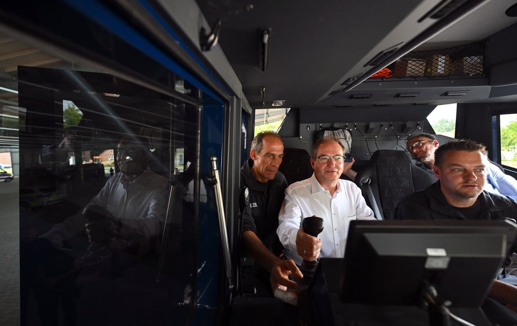Bundesinnenminister Alexander Dobrindt lässt sich die Funktionsweise eines Wasserwerfers erklären und steigt dafür auch selbst in das Fahrzeug.