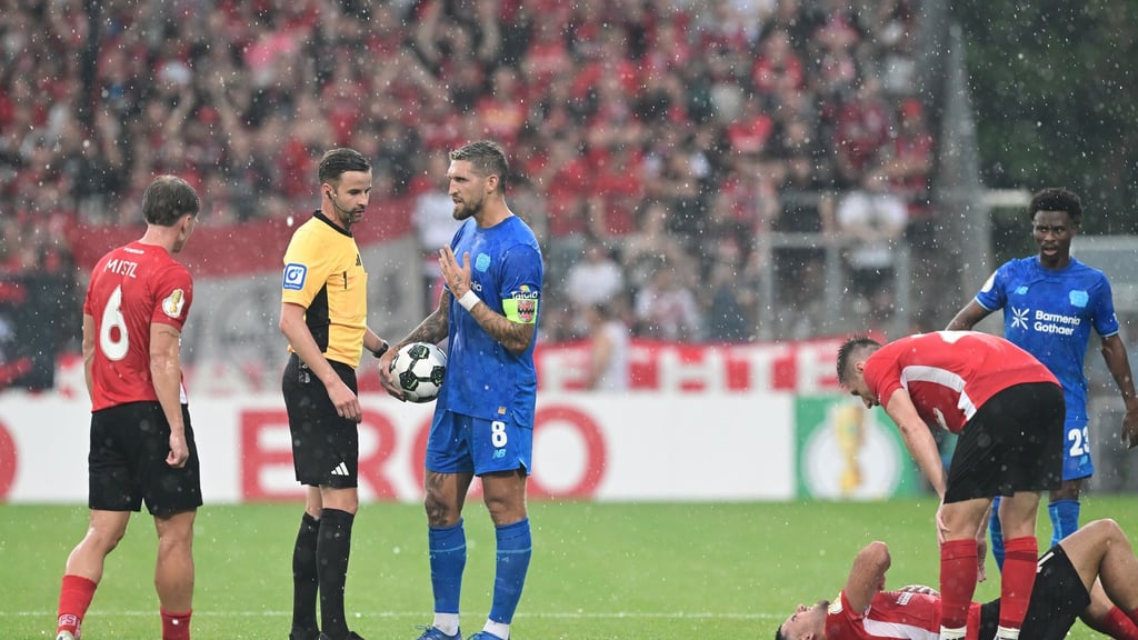 Schiedsrichter Michael Bacher (2.v.l.) muss das Spiel in Großaspach unterbrechen