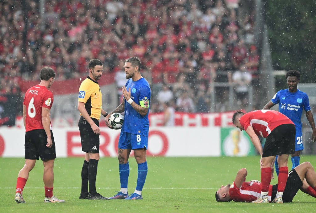 Schiedsrichter Michael Bacher (2.v.l.) muss das Spiel in Großaspach unterbrechen