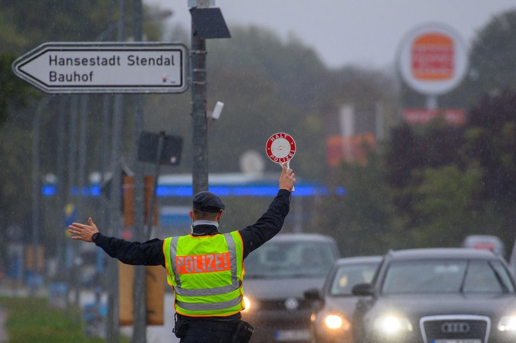 Ein Polizist winkt mit einer Polizeikelle einen Autofahrer aus dem Straßenverkehr. (Archivbild)