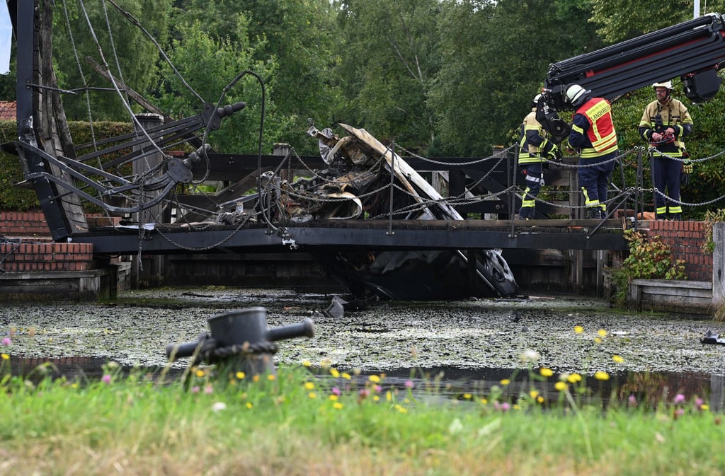 Einsatzkräfte bergen das Wrack eines verbrannten Autos, dass in Papenburg in einen Kanal gefallen ist.