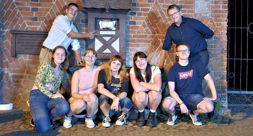 Der Puparsch-Bierbrunnen hat einen Übergangs-Po aus Kreppband bekommen. Bürgermeister Olaf Meining (rechts) unterstützte den lustigen Ensatz.