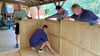 Die Pächter Mario Kempe (re.) und Bernd Bruder (li.) bauen mit Helfern eine Hütte am Froser See auf.