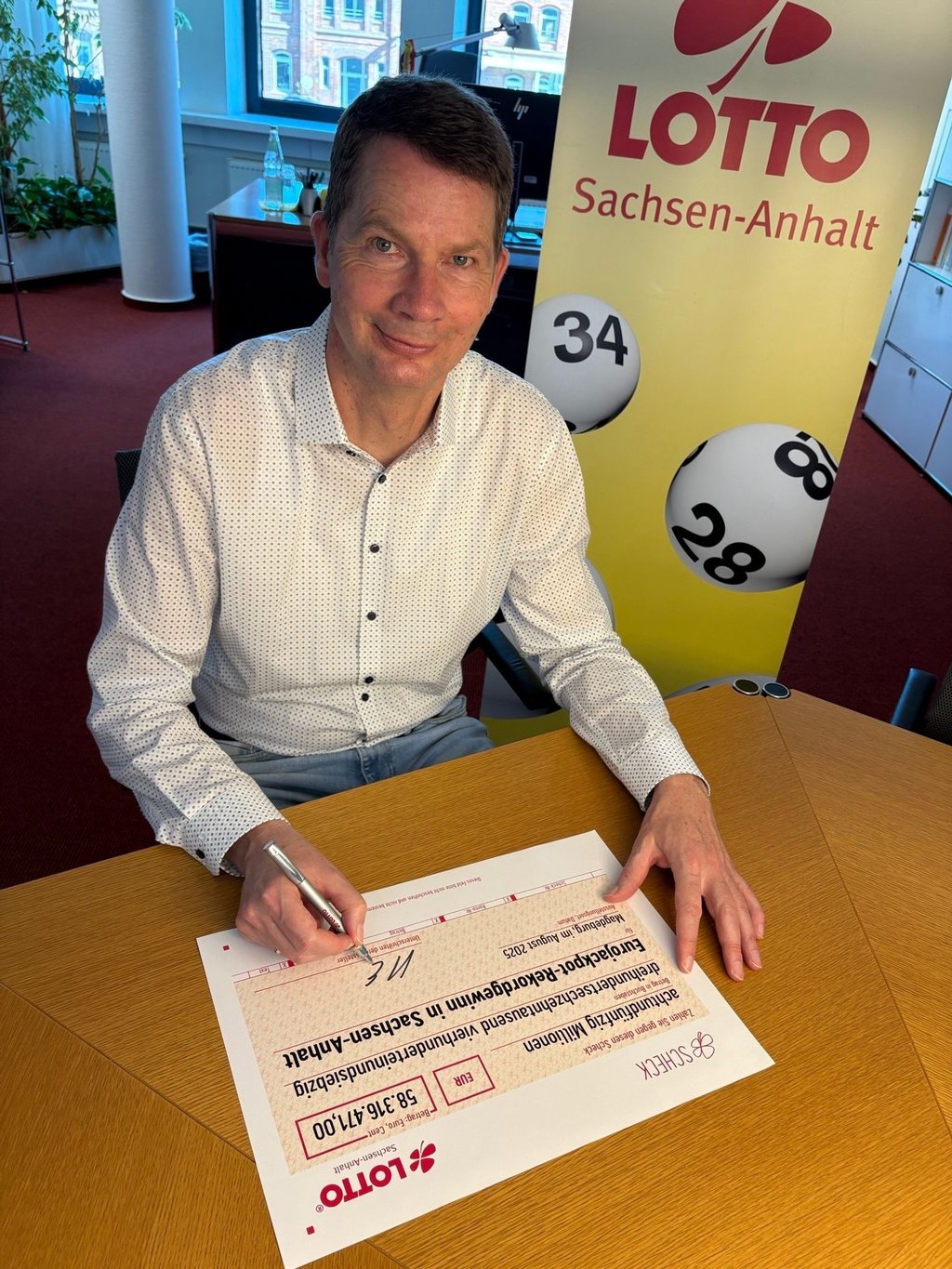 Der Scheck, den Lotto-Geschäftsführer Stefan Ebert unterschreibt, ist symbolisch. Das Geld wird auf das Konto des Gewinners überwiesen.