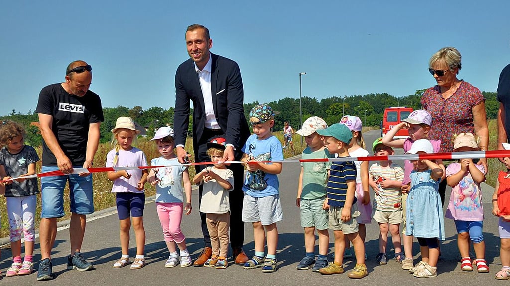 Oberbürgermeister Bastian Sieler (Mitte) schneidet im Stendaler Ortsteil Uenglingen gemeinsam mit Kindern der Kita Spatzennest das Band an der Straße Ackerwinkel durch und eröffnet somit feierlich das neue Wohngebiet.