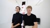 Die Künstler Ana Zibelnik (l) und Jakob Ganslmeier sitzen vor der von ihnen geschaffenen vier Meter hohen Videoskulptur zu neofaschistischem Körperkult auf TikTok in den Räumen des Museums für Zwangsarbeit vor der offiziellen Eröffnung des Kunstfests Weimar 2025.