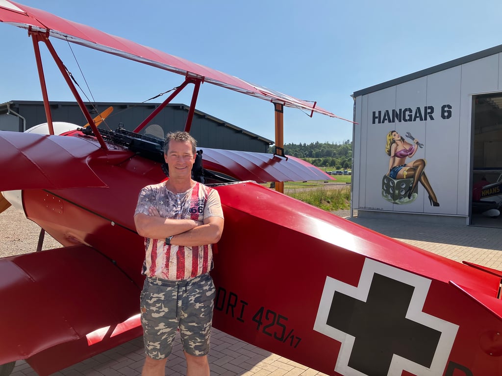 Alexander Stegner, Flugzeugmechaniker und Kunstflieger, vor seinem Nachbau der Fokker Dr. I und seinem Hangar auf dem Ballenstedter Flugplatz.