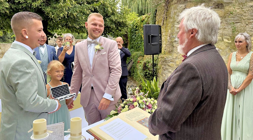 Vor dem Standesbeamten Uwe Lachmuth schlossen Jesse Manuel Bertram (links) und Kevin Roßberg unter freiem Himmel auf der Wasserburg in Egeln den Bund fürs Leben. Die kleine Zoe reichte dem Paar die Ringe.