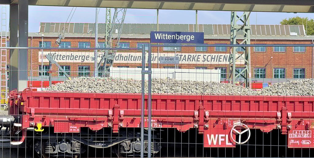 Auf den Gleisen des Bahnhofs Wittenberge stehen Güterwaggons mit Baumaterialen wie Schotter.