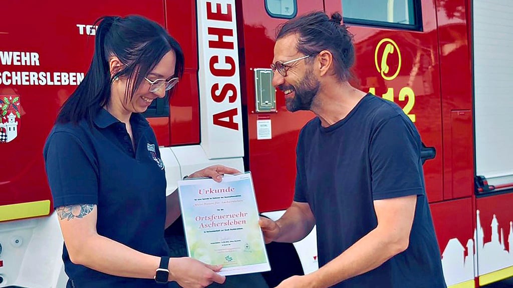 Debby Heinze von der Aschersleber Feuerwehr nimmt die Urkunde für den Baum von Silvio Merkwitz vom Verschönerungsverein entgegen.