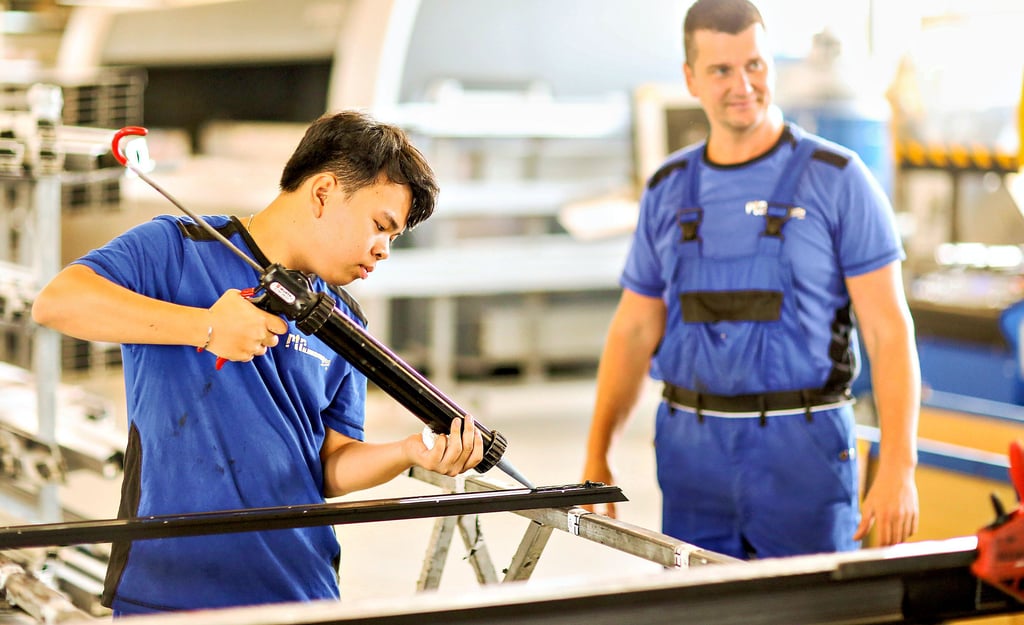 Thanh Nhat Ngo lernt bei RTR-Aluminiumbau den Beruf des Metallbauers. Er arbeitet in der Werkhalle. Hier im Foto mit Ausbildungsleiter André Martin