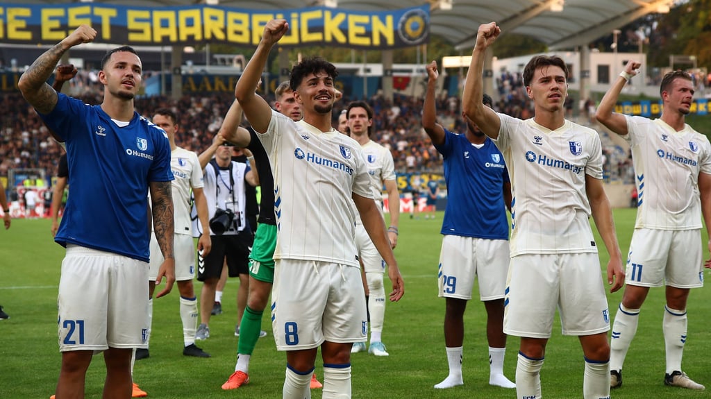 Falko Michel (v. l.), Laurin Ulrich und Noah Pesch feiern den Sieg ihres 1. FC Magdeburgs gegen den 1. FC Saarbrücken.