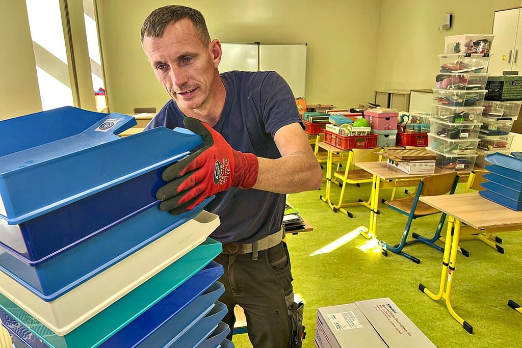 Stefan Zorn räumt Ablagen in den Raum der vierten Klasse.