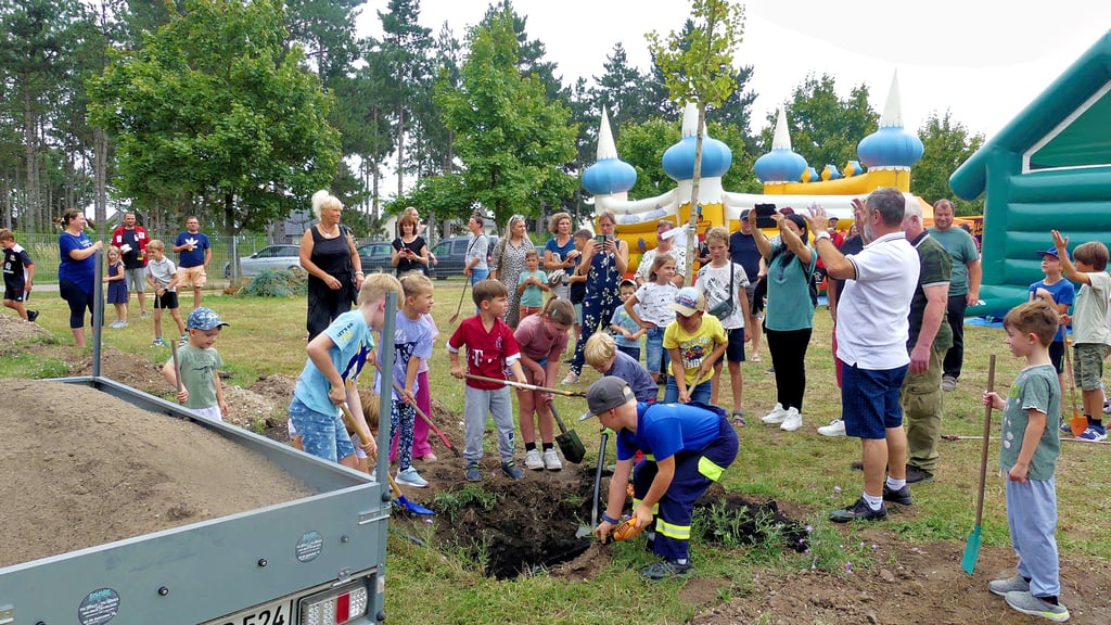 Kinder aus den Vereinen und der Grundschule Brehna setzen gemeinsam einen jungen Baum für den Naturlehrpfad in die Erde.