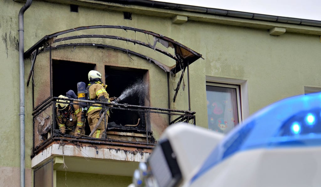 Kameraden löschen auf dem Balkon der Brandwohnung im 4. Stock letzte Glutnester an der Wandverkleidung.