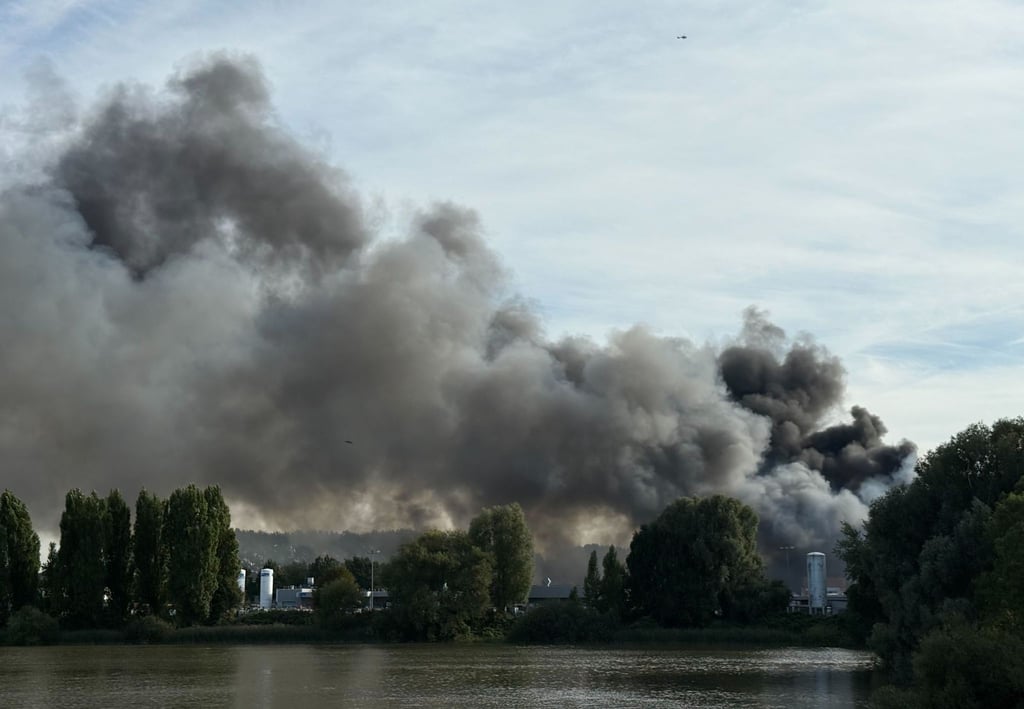Eine große Rauchwolke breitet sich über einem Gewerbegebiet hinter dem Müggenburger Kanal aus.
