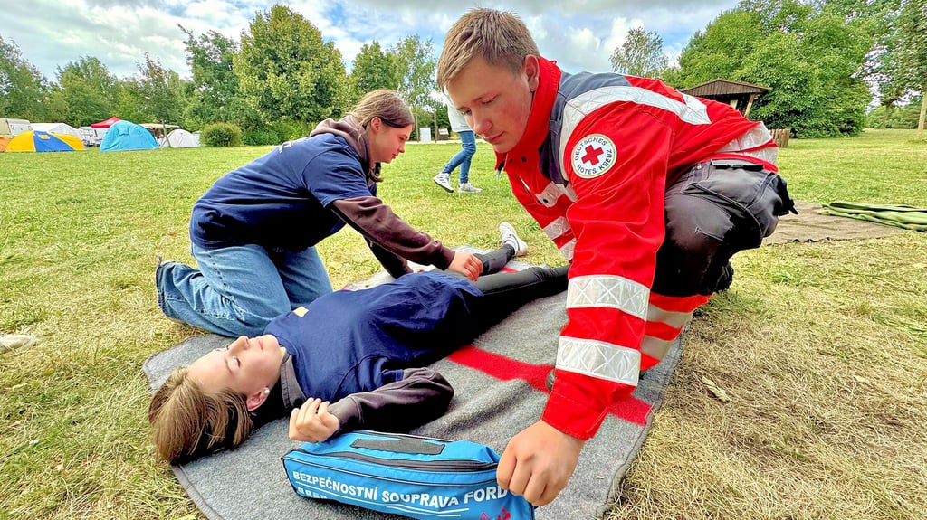 Ben Netzel (rechts) vom DRK Jessen erklärt den Teilnehmern, welche Griffe für eine stabile Seitenlage notwendig sind.