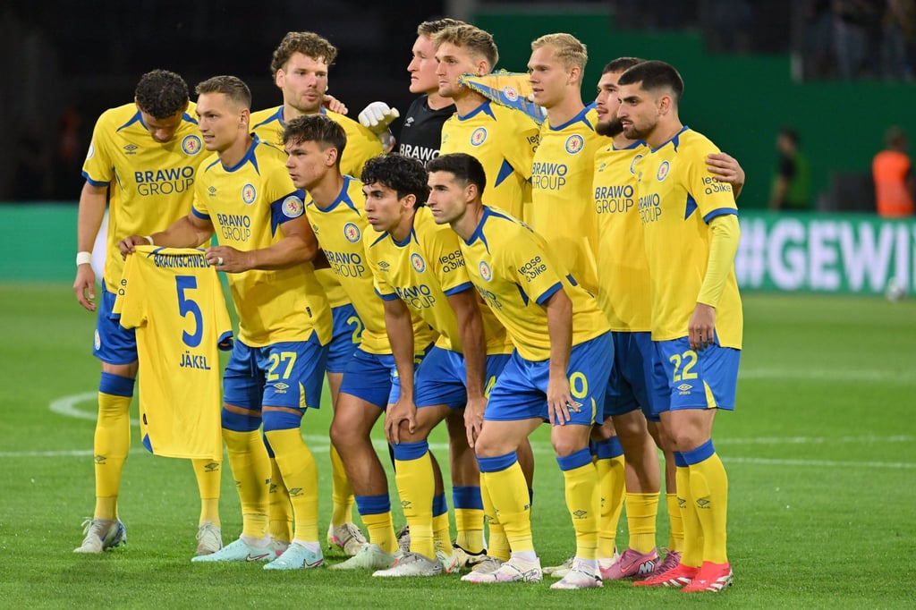 Mitleid mit dem Teamkollegen: Die Braunschweiger halten vor dem Pokalspiel gegen Stuttgart ein Trikot des verletzten Frederik Jäkel hoch.
