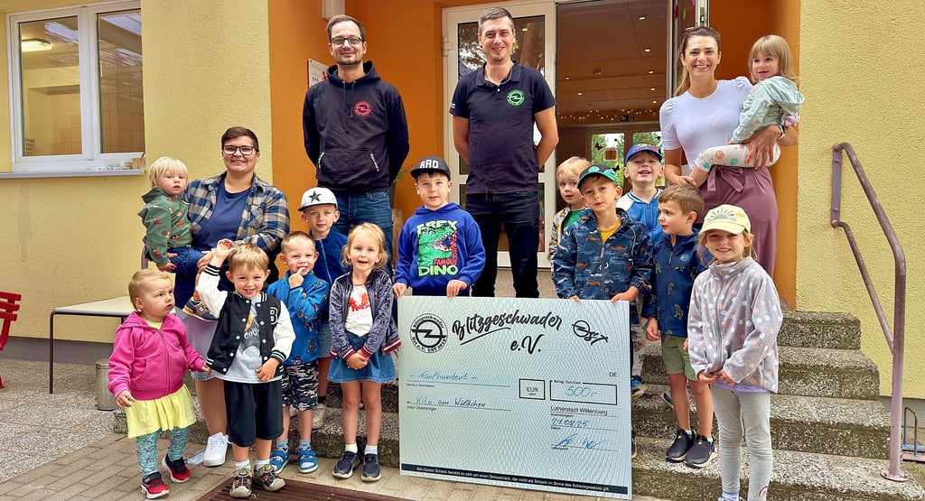Mario Freydank und Marcus Sandau vom Verein „Blitzgeschwader Ost“ übergeben Bergwitzer Kita einen Scheck über 500 Euro.