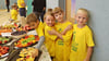 Die Jungen und Mädchen der ersten Klasse probieren sich durch das Obst und Gemüse, das zum Teil aus dem Schulgarten stammt.