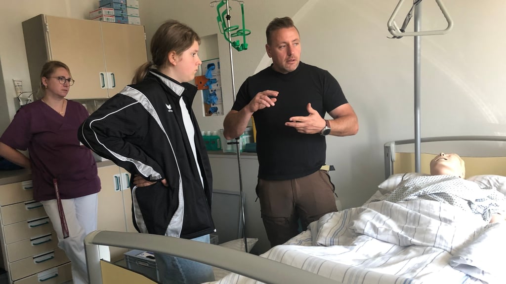 Christopher Weller-Bock erklärt Schülerin Thea Bierbach, dass es im Schulungsraum im Harzklinikum in Quedlinburg verschiedene Phantome für unterschiedliche Praxisübungen gibt. Links im Bild Anne Poprawa, Gesundheits- und Krankenpflegerin und Zentrale Praxisanleiterin.