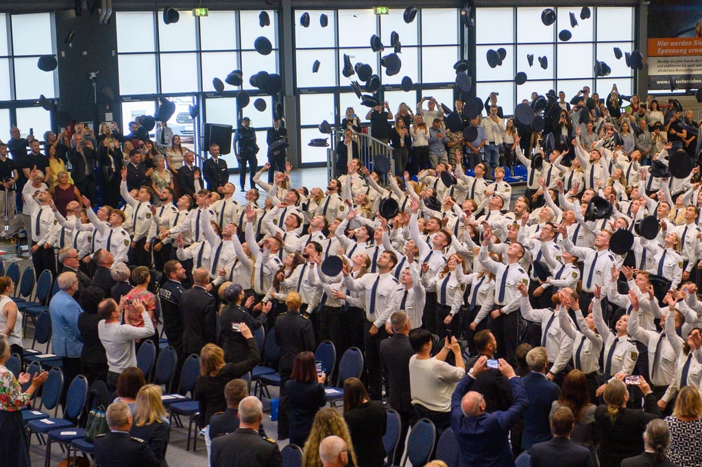 Absolventen der Fachhochschule Polizei Sachsen-Anhalt werfen ihre Dienstmützen in die Luft.