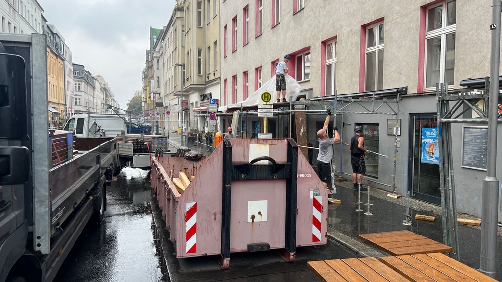 An einem Haus mit einem beschädigten Dach wird ein Schutztunnel für Fußgänger aufgestellt.