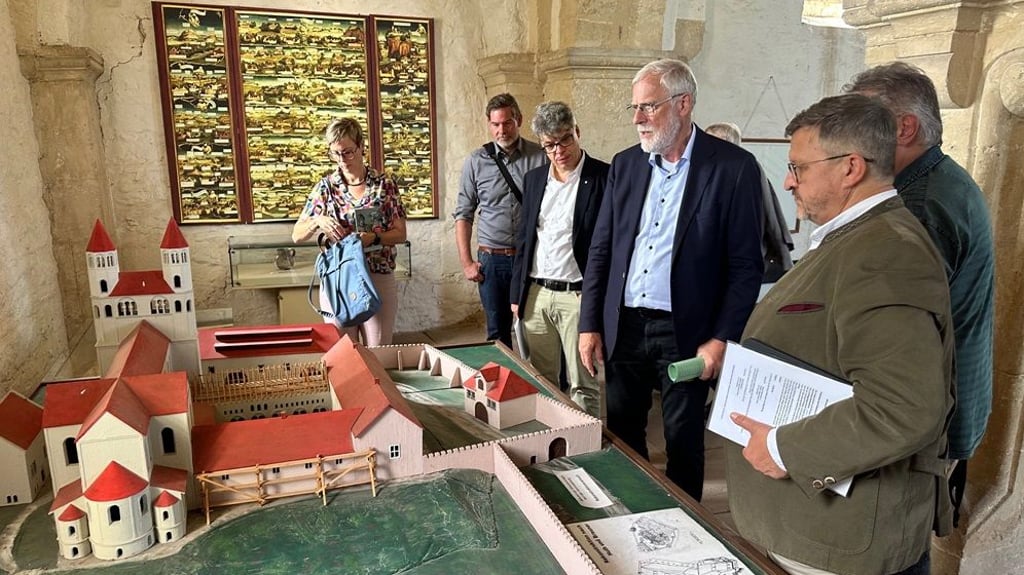 Kulturminister Rainer Robra (4.v.l.) sieht sich auf der Konradsburg ein Modell der Burg an. Die Nordscheune soll ein neues Dach bekommen.