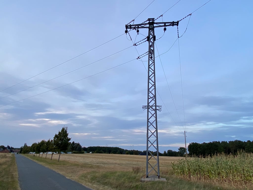 An dieser Stelle sollen die Schwerlasttransporte, von der Brache kommend, auf die Ziegelei-Straße auffahren. Geprüft wird aktuell, ob sie zwischen den Linden (links im Bild) und dem Gitterstrommast hindurch passen werden.