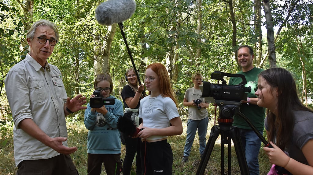 Ranger Ulf Damm (l.) spricht vor der Kamera. Paul Braatz (2.v.l.), Viktoria Schliephake (3.vl.), Nikki-Michell Stein (mitte), Nick Stegemann (3.v.r.) und Luna Craas (r.) gehören zum jungen Film-Team im Drömling. Projektmitarbeiter Oliver Krebs gibt die fachlichen Anleitungen.