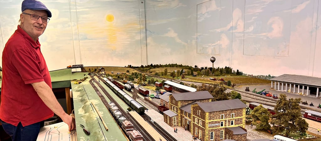 Am digitalen Bedienpult der großen Anlage steht Olaf Bauermeister aus Bismark. Vor ihm befindet sich die nachgebaute Bahnhofsanlage von Schönhausen, wie sie sich zu DDR-Zeiten präsentierte. Hinter dem Bahnhof sieht man die roten Schienenbusse der Kleinbahn.