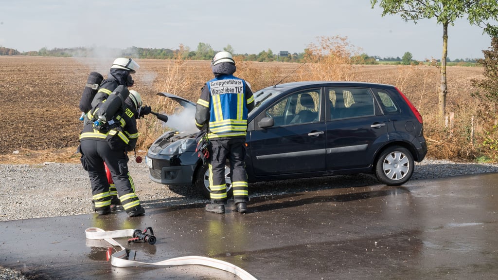 Die Einsatzkräfte aus Wanzleben löschen den Brand im Motorraum eines Pkw auf der Landesstraße 50.