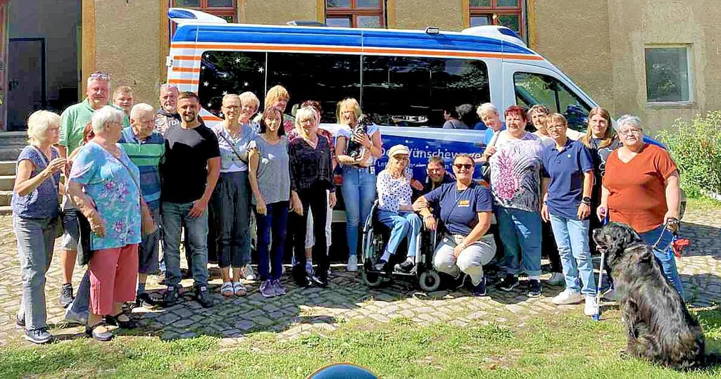 Freunde, Familie, Klassenkameraden – sie alle stellen sich gemeinsam mit Birgit Skibowski vor dem Wünschewagen zu einem Gruppenfoto auf.