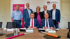 Die Bürgermeister stehen hinter Landrat Christian Tylsch (sitzend links) und Telekom-Vertreter Axel Wenzke während der Vertragsunterzeichnung.