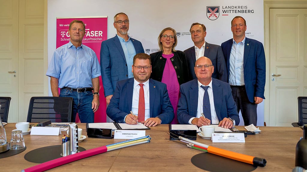 Die Bürgermeister stehen hinter Landrat Christian Tylsch (sitzend links) und Telekom-Vertreter Axel Wenzke während der Vertragsunterzeichnung.