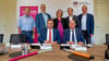 Die Bürgermeister stehen hinter Landrat Christian Tylsch (sitzend links) und Telekom-Vertreter Axel Wenzke während der Vertragsunterzeichnung.
