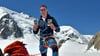 Bergsteiger Denis Liedke am Mont Blanc auf dem Gletscher im Vallée Blanche. Er hält ein Bild von seinen Kindern und eines von seinen Großeltern in den Händen.