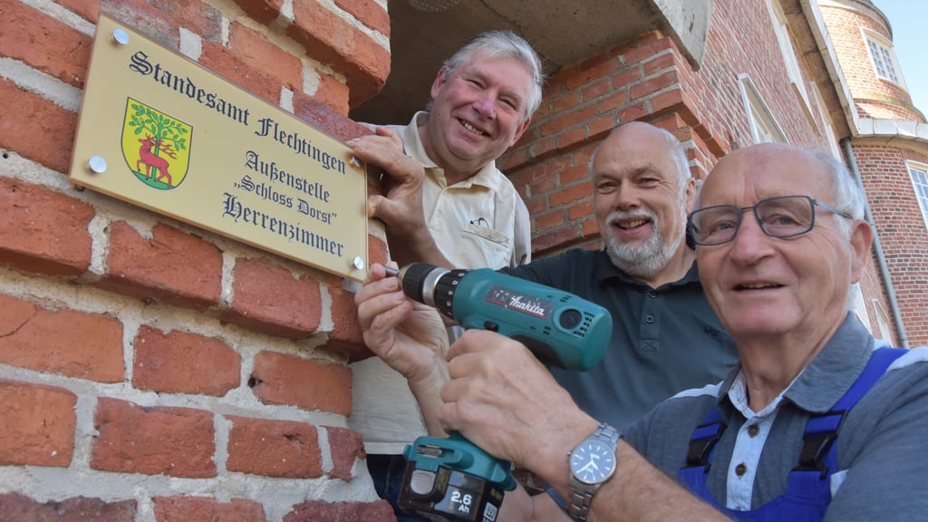 Manfred Franke (von vorn), Wolfram Materne und Ingo Springborn von der Interessengemeinschaft Dorst bringen das Schild „Standesamt Flechtingen/Außenstelle Schloss Dorst“ am Eingang vom Gutsherrenhaus an.