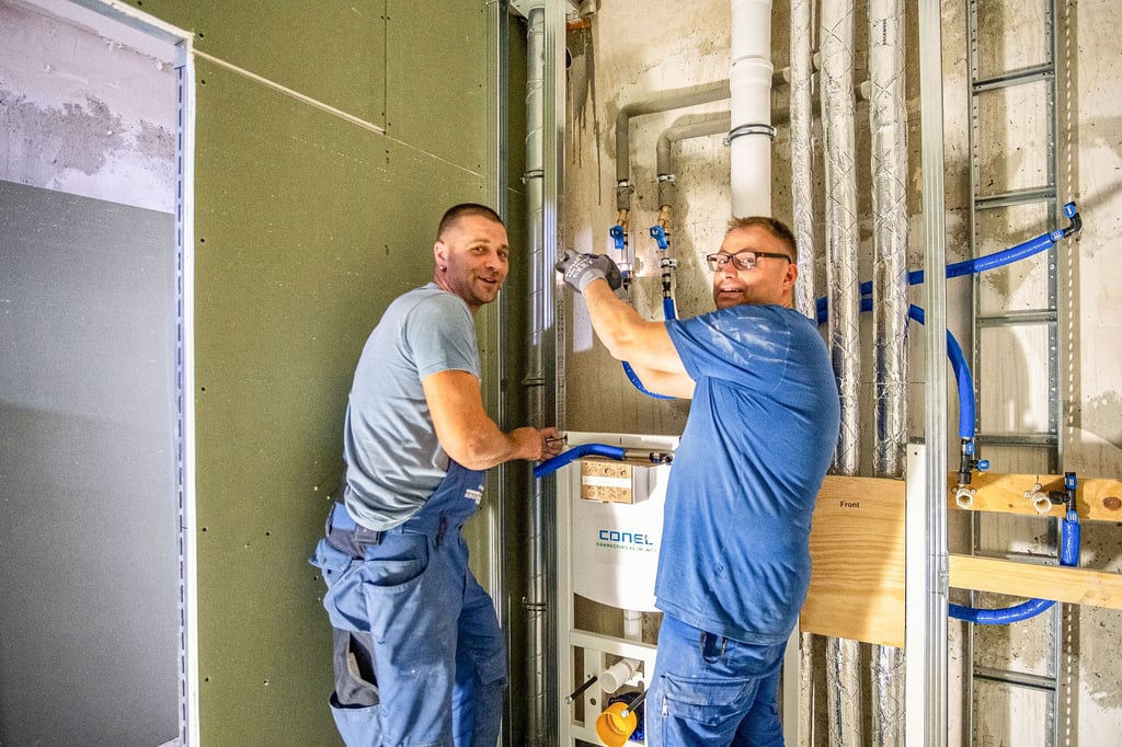 Robert Klotz (l.) und Max Zschach arbeiten in einem der neuen Bäder an der Sanitärinstallation.
