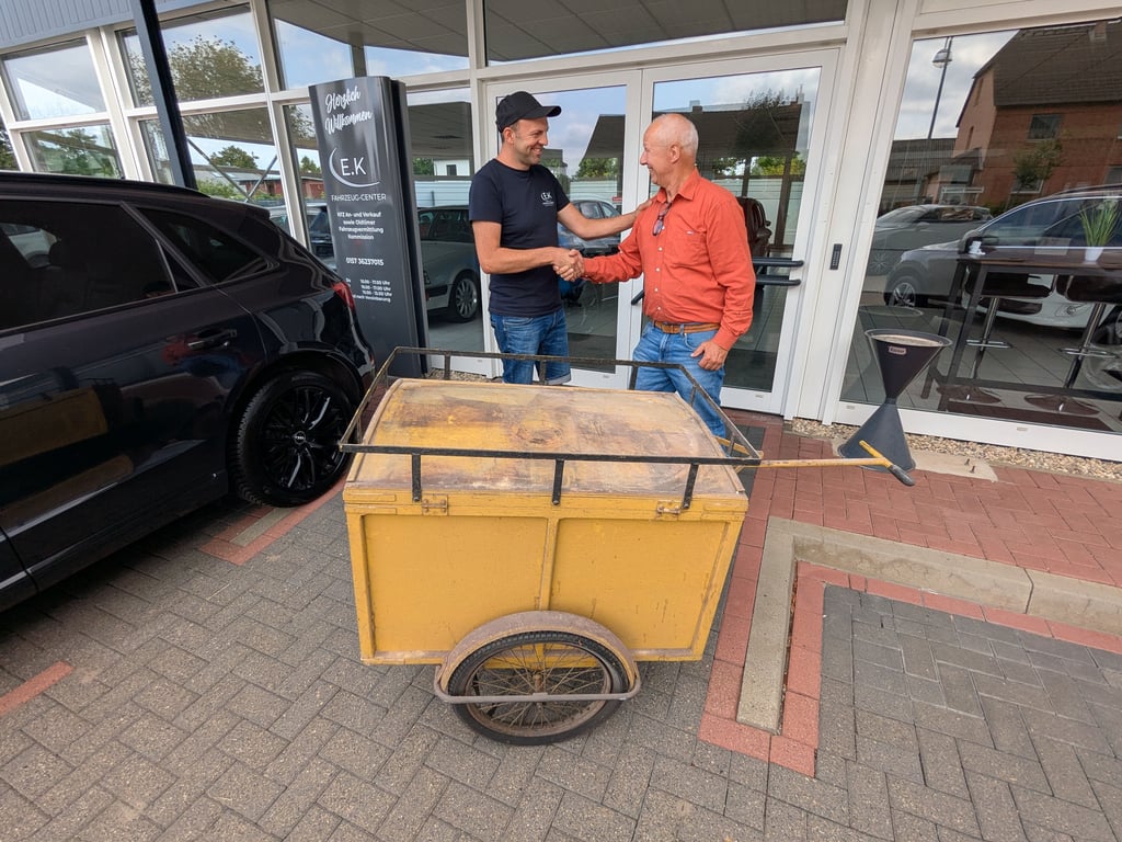 Erik Koschnick übergibt dem Vorsitzenden des Heimatvereins Ulrich Pettke vor dem Autohaus an der Stendaler Straße das historische Fahrzeug für die Sammlung des Burg- und Heimatmuseums.
